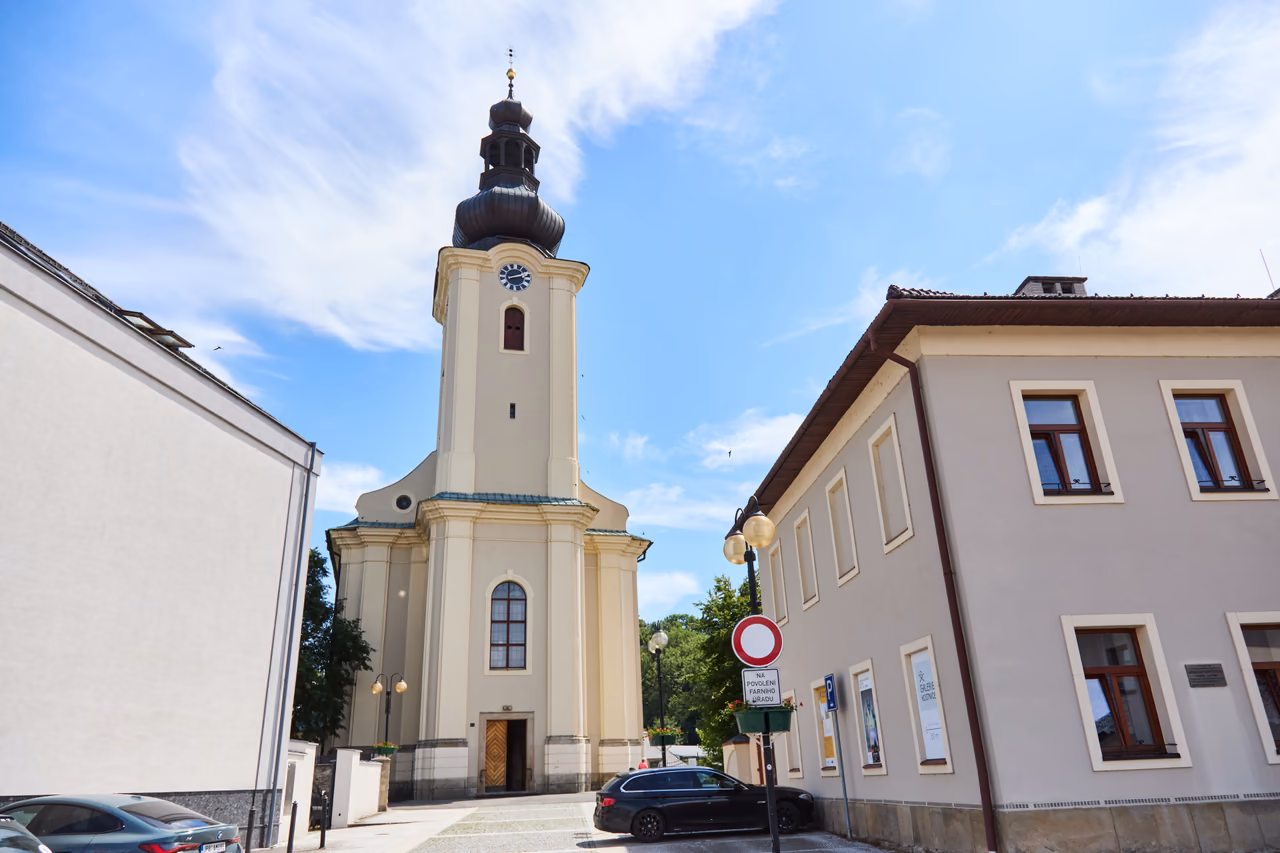 Fasada kościoła Wszystkich Świętych z wieżą i głównym wejściem, po prawej budynek ze wskazówką do Galerie Kostnice