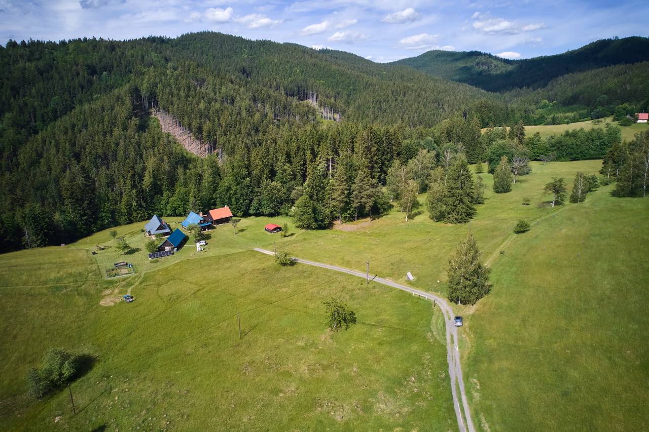 Letecký pohled na paseky nad Horní Bečvou z jiného úhlu - chalupy na okraji luk, kolem smrkový les