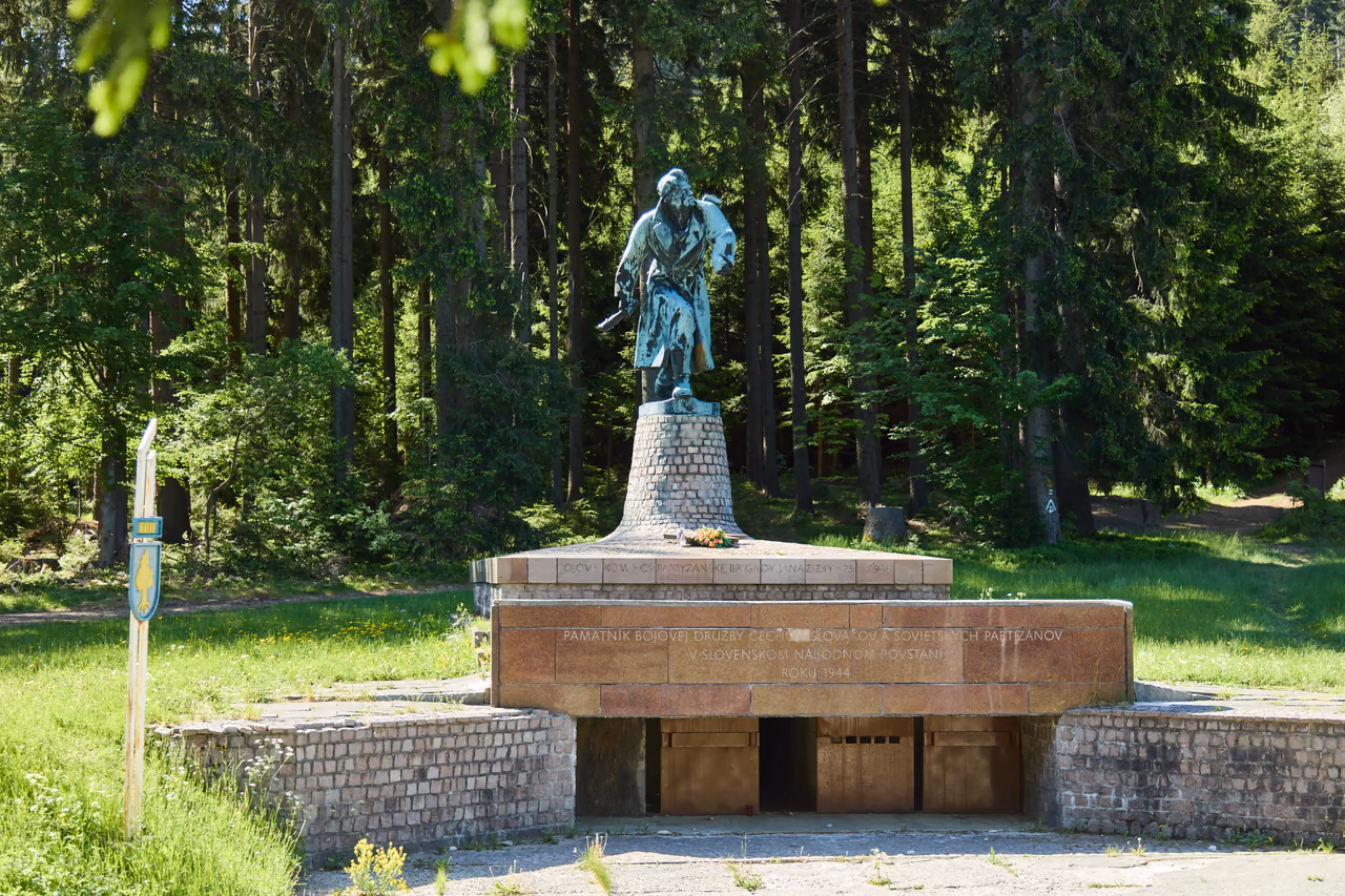 Památník s oběma nápisy zepředu, vlevo cedule se znakem obce Makov