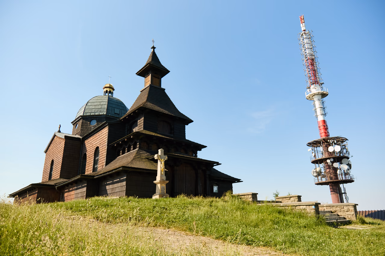 Kaple sv. Cyrila a Metoděje z boku, s vysílačem a kamenným křížem před vchodem