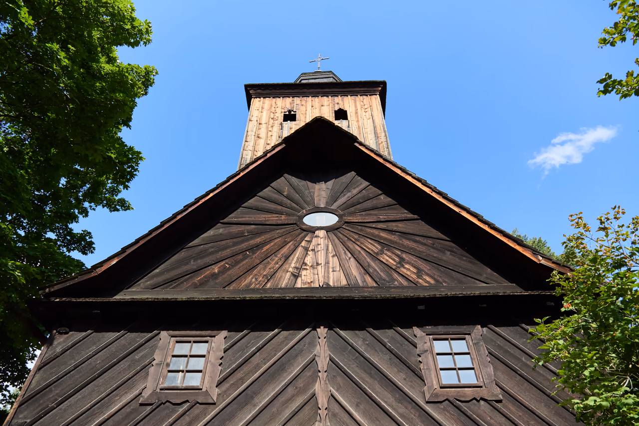 Giebel und Turm der Kirche von unten, Bretterverschalung und Schindeln gegen den Himmel