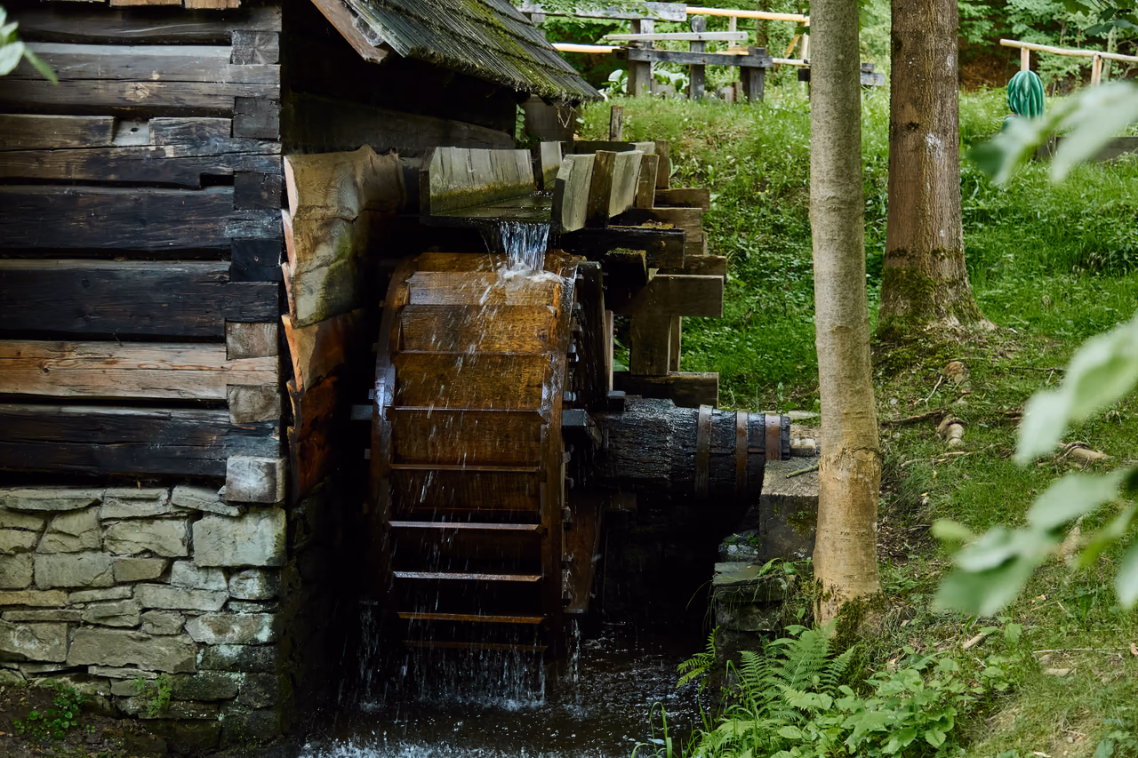 A water wheel turning – water falling onto its paddles from a wooden millrace