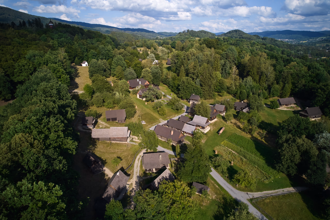 Aerial view of the Wallachian Village – cottages among meadows, the Jurkovič lookout tower on the hill to the left