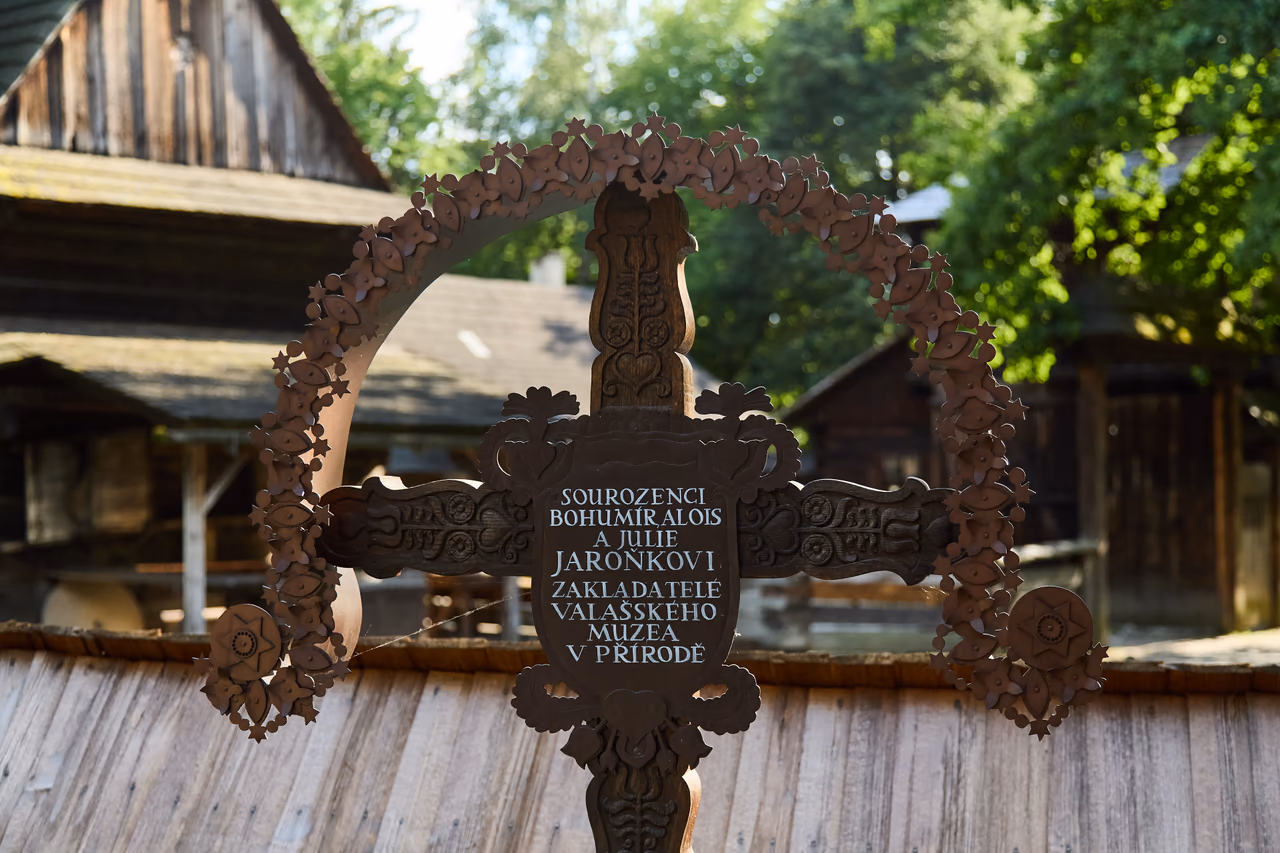 Geschnitztes Holzkreuz mit der Tafel „Sourozenci Bohumír, Alois a Julie Jaroňkovi, zakladatelé Valašského muzea v přírodě“