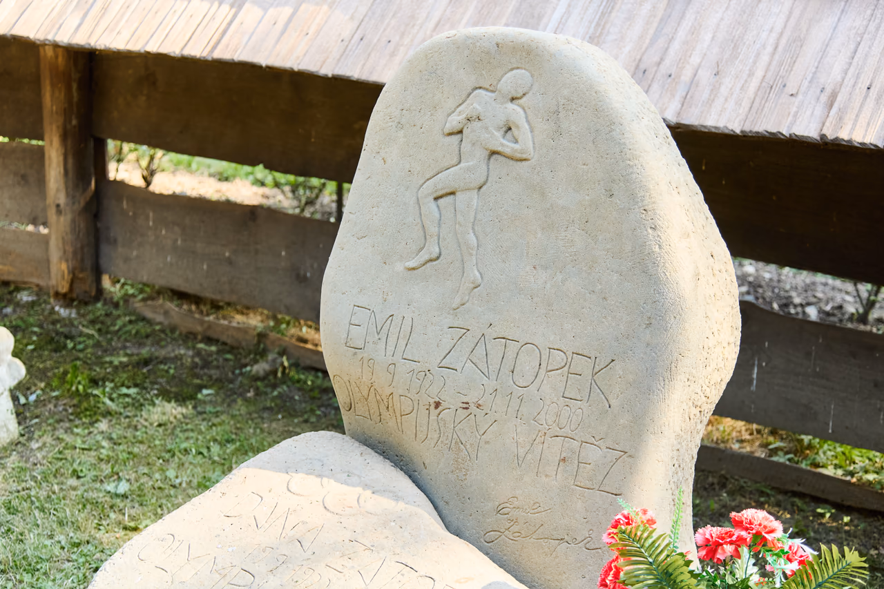 Grabstein von Emil Zátopek aus Sandstein mit dem Relief eines Läufers, daneben die Tafel von Dana Zátopková