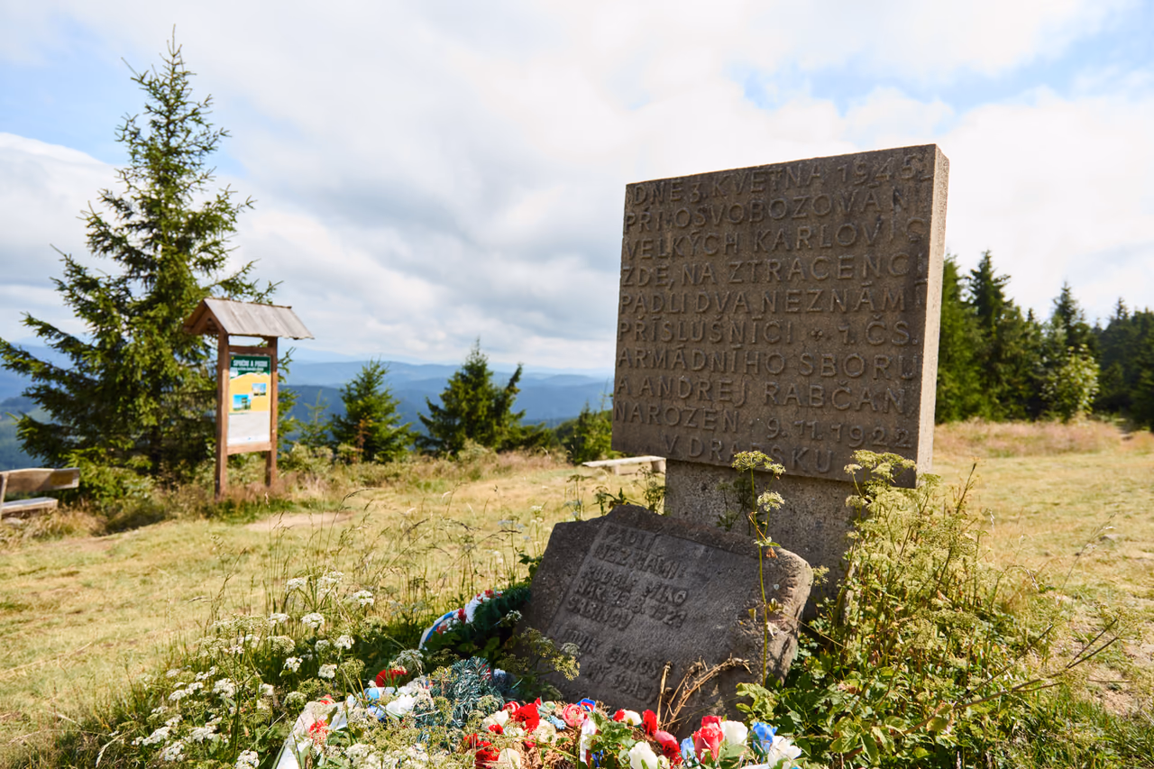 Kamenná deska pomníku s vytesaným nápisem o 3. květnu 1945, před ní menší kámen a věnec v národních barvách