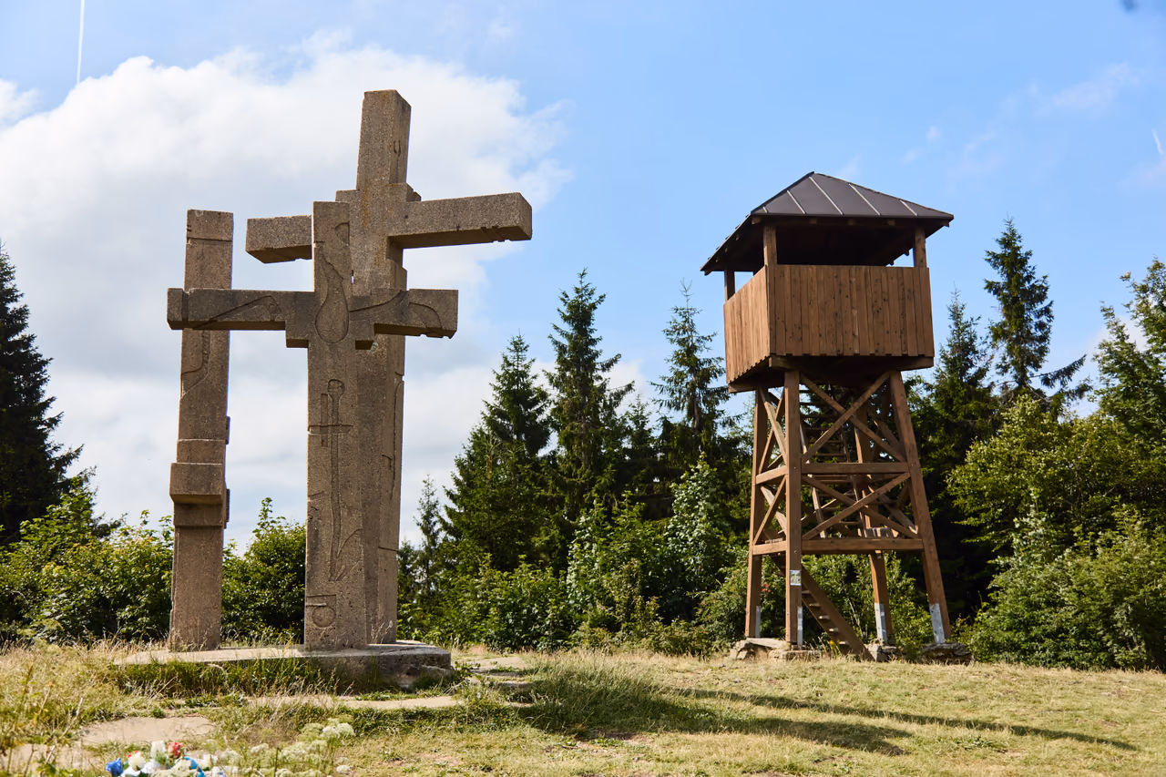 Tři kříže a vedle nich dřevěná rozhledna na šikmých nohách s krytou vyhlídkovou budkou