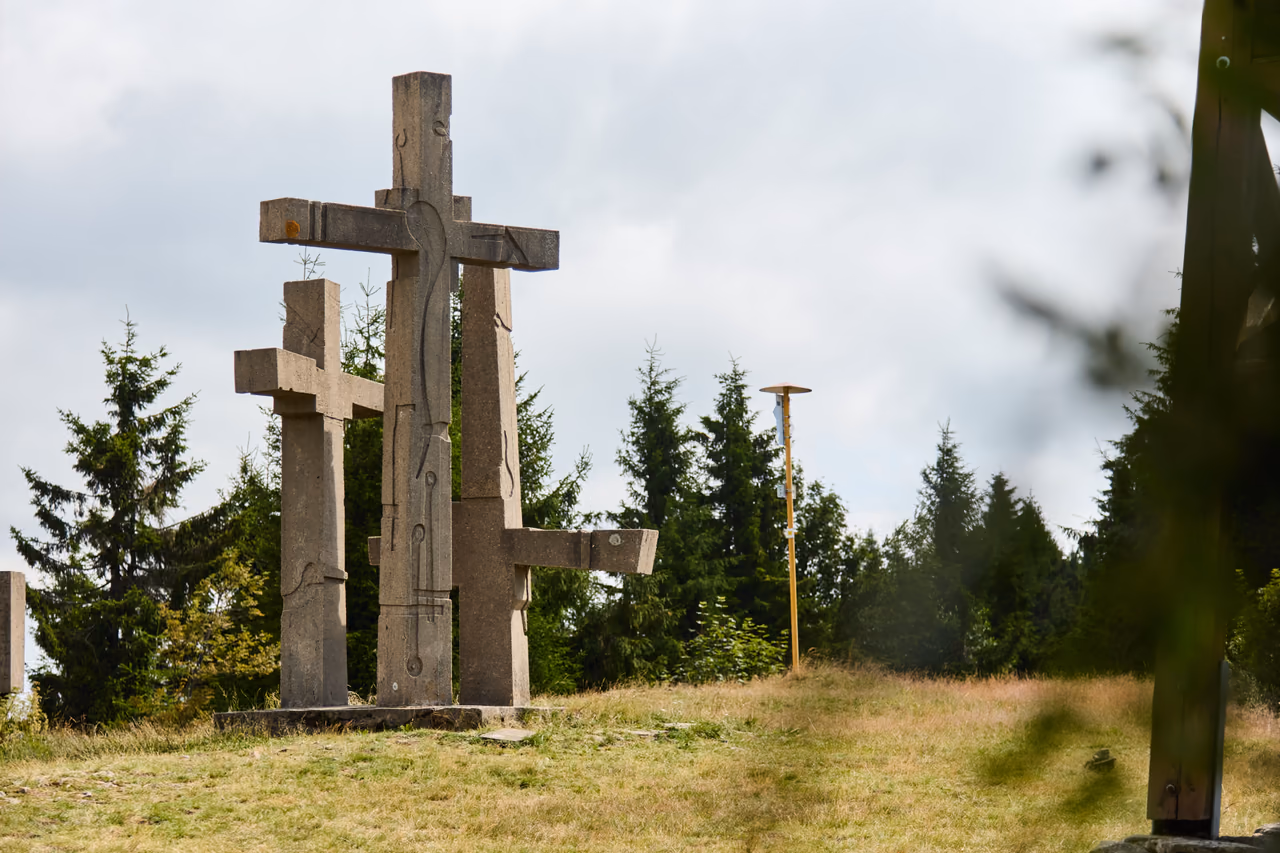 Tři kříže na vrcholové mýtině zarámované větvemi stromu